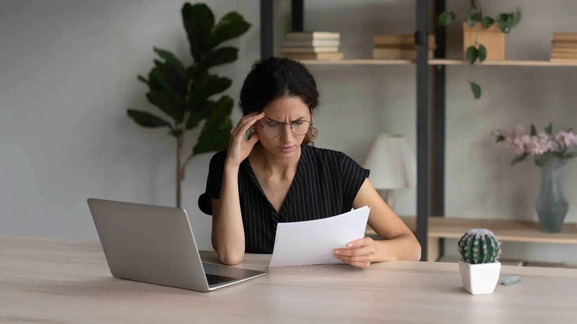 Mujer preocupada revisando documentos legales en su laptop, representando la defensa ante embargos de bienes.