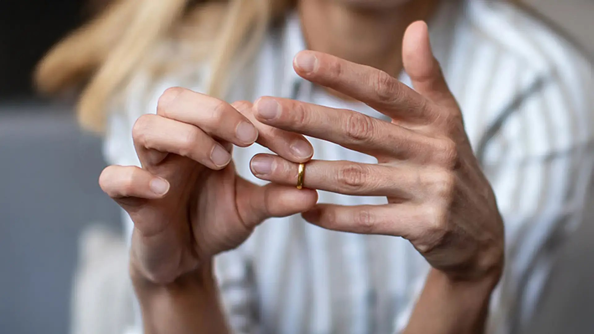 Persona quitándose una alianza matrimonial, representando servicios legales de divorcio.