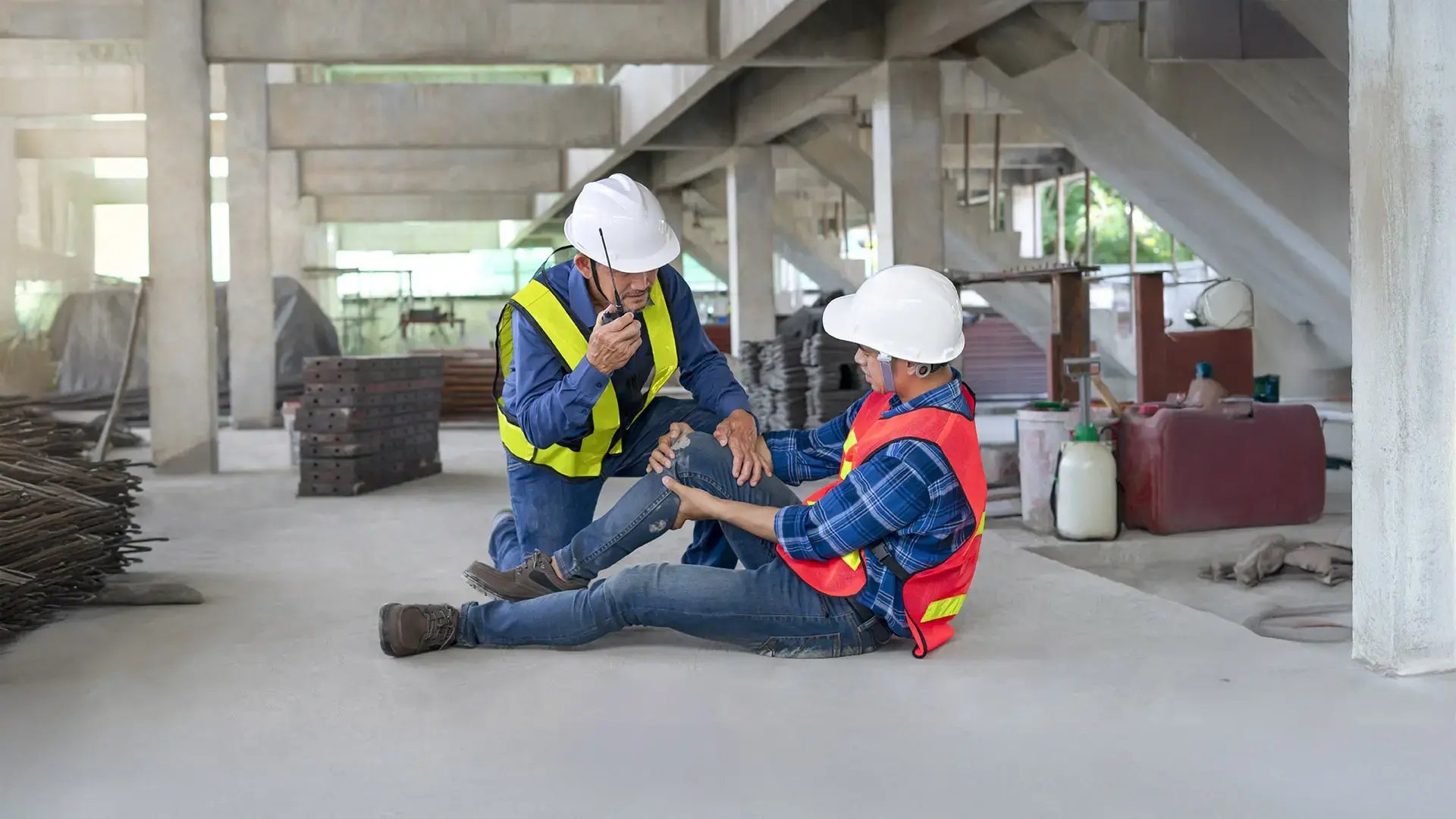 Trabajador de la construcción siendo asistido por un compañero tras sufrir un accidente laboral en una obra.