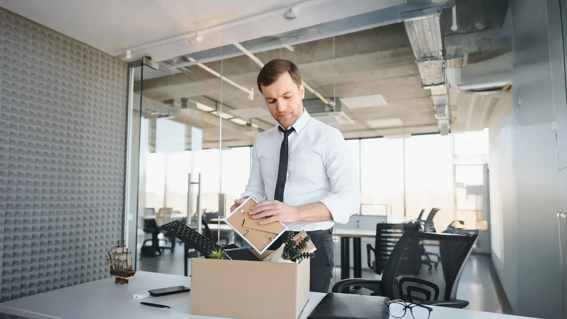 Hombre de negocios guardando sus pertenencias en una caja tras decidir un autodespido laboral.