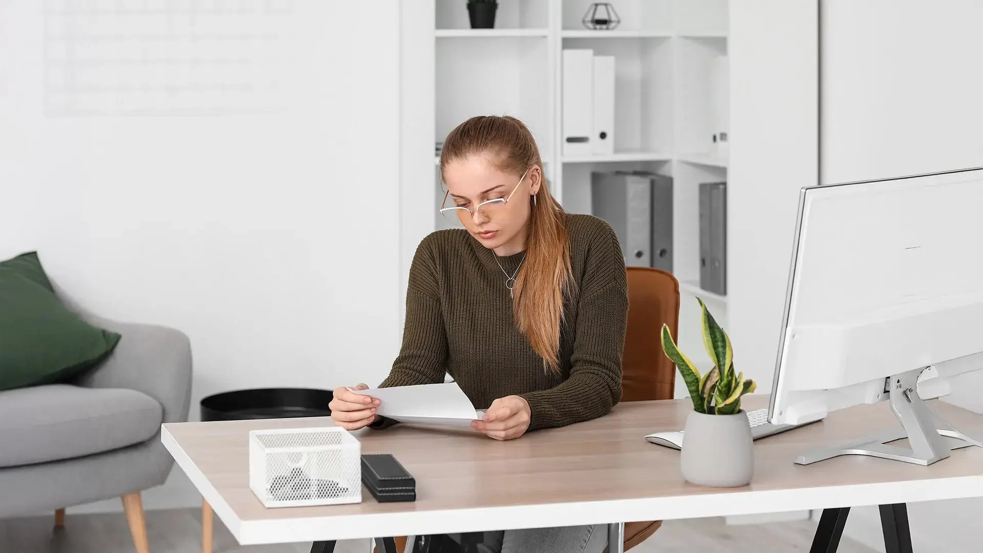 Mujer revisando seriamente una carta de despido en su escritorio de oficina.